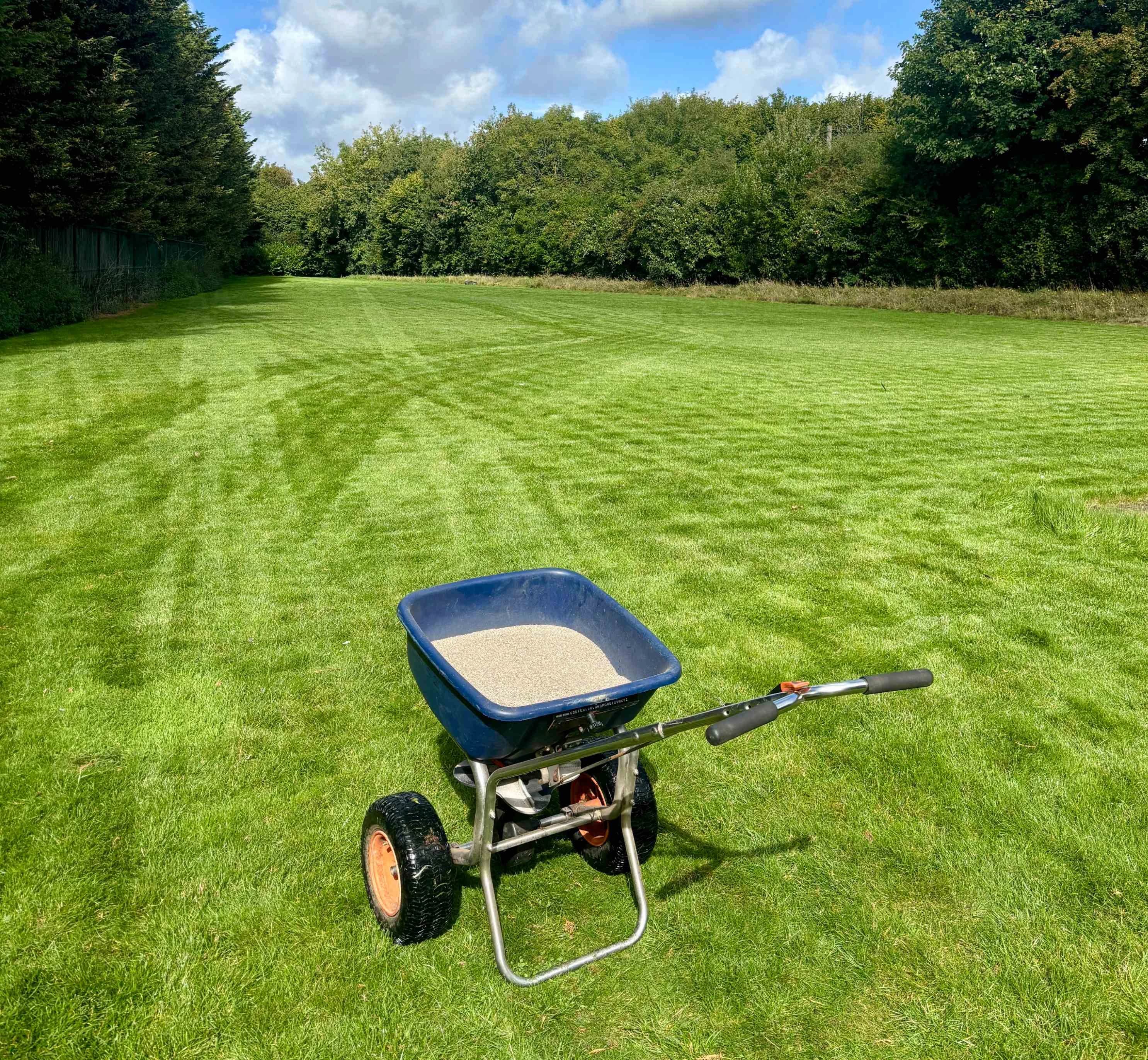 Image of fertiliser spreader on a large striped lawn